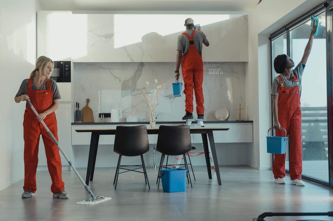 gallery-3 Group of cleaners in red uniforms mopping and wiping glass in a modern dining room.